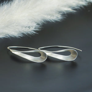Garden of Desire - Fold in Silver Earrings Handcrafted in matte sterling silver, these 4cm-long earrings dangle just below the earlobe, opening up gently into a rounded, graceful fold, exuding a timeless allure.