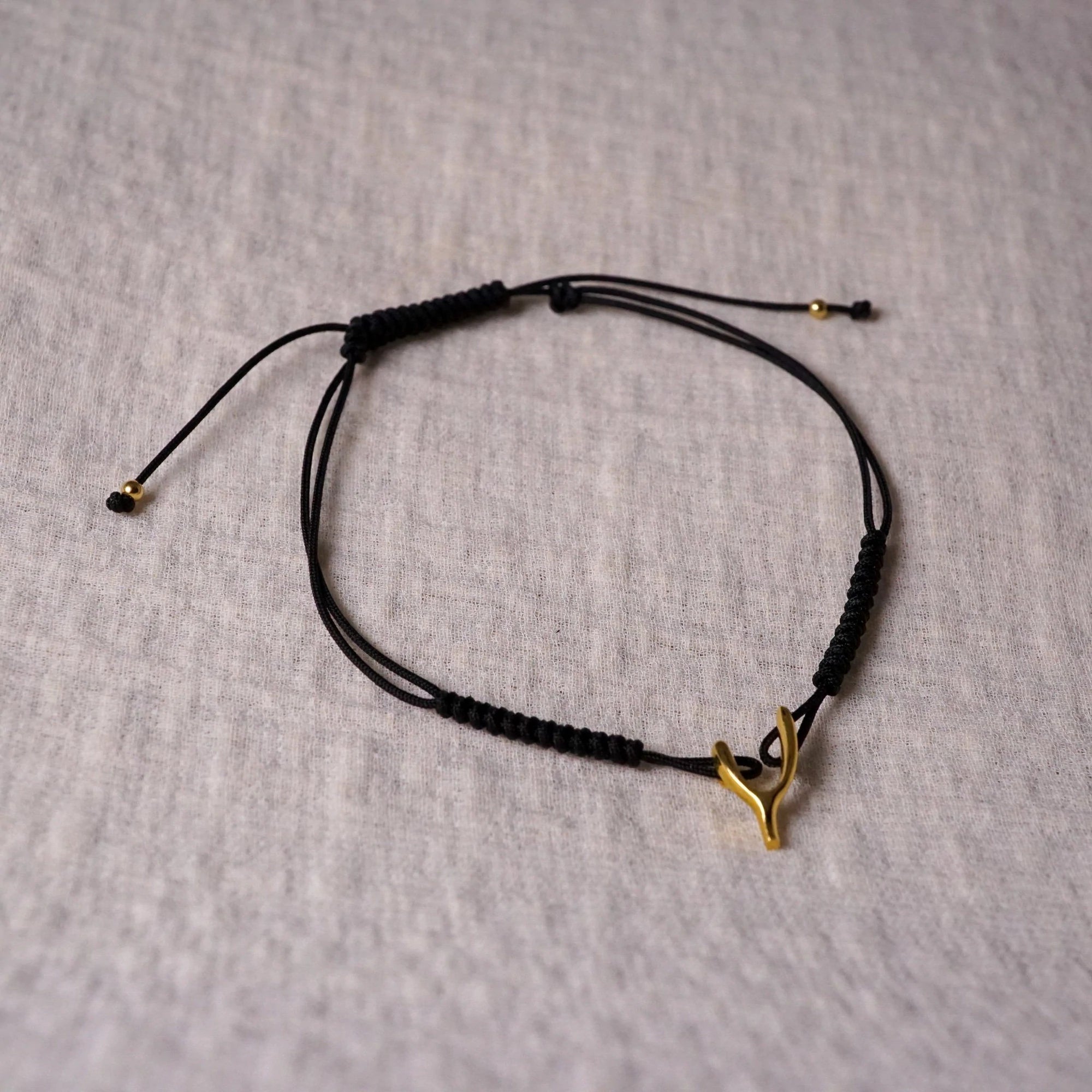 Garden of Desire - Wishbone Bracelet A symbol of hope, this adjustable braided drawstring bracelet in black features a handcrafted 92.5 sterling Wishbone charm.